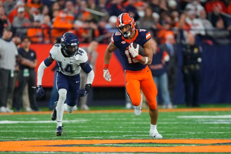 SYRACUSE, NY - NOVEMBER 23: Syracuse Orange Tight End Oronde Gadsden II (19) runs with the ball against Connecticut Huskies Defensive Back Malcolm Bell (14) during the second half of the College Football game between the UConn Huskies and the Syracuse Orange on November 23, 2024, at the JMA Wireless Dome in Syracuse, NY. (Photo by Gregory Fisher/Icon Sportswire via Getty Images)Gregory Fisher/Icon Sportswire via Getty Images